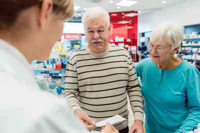 pharmacist getting prescription slip from senior couple
