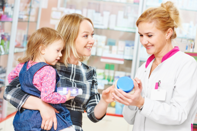 female pharmacist and mother holding a child smiling